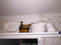 Shelf with white ceramic platter, brown bird container, white ceramic rabbit casserole with lid, and white bird pitcher.