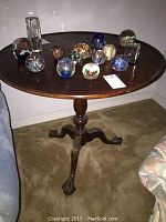 Full view of the round wood table with multiple decorative glass paperweights on top.