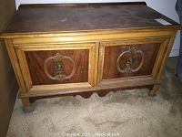 Full front view of wood cabinet showing two carved panel doors with brass handles, top surface with wear marks.