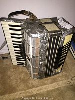 Full view of Weltmeister piano accordion on carpet showing keyboard, bellows, grille and shoulder straps.