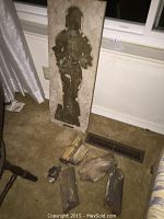 Full view of carved stone art directing upright with assorted petrified wood pieces lying in front on carpet