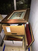Stack of assorted frames on and inside cardboard boxes, showing size range and styles