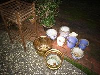 Photo showing entire collection of various sizes and styles of gardening pots and wooden plant stand and table on outdoor surface