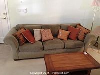 Front view of the dark green/grey Havertys couch with six throw pillows arranged on it.