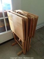 4 wooden folding TV tray tables folded and stored upright in a wooden rack