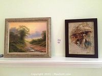 Two framed paintings mounted on a wall: a scenic meadow landscape and a textured portrait of a man wearing a woven hat.