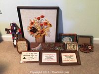 Overview of lot showing all items including framed crocheted floral piece, carved wood plaques, framed sayings, and small decorative items.