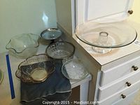 Six assorted serving bowls and trays including silver plate and cut glass pieces on kitchen counter.