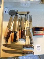 Collection of various kitchen knives and tools displayed on countertop.