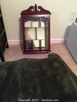 Photo showing solid cherry wood display cabinet with glass door and mirrored back panel.
