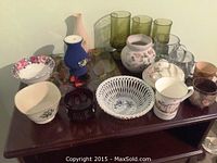 Wide shot of assorted glass and porcelain decorative items on dark wooden table.