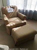 Front angle of beige reclining chair with ottoman, shows chair and ottoman in sitting position with sunlight through window.