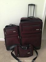 Full view of the three luggage items - two upright suitcases and one travel bag on carpeted floor.