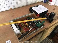 Overview of tools on a workbench including cordless drill, hand tools in box, and case