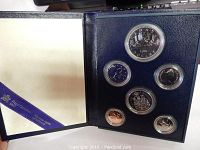 Open navy blue display case showing six Canadian coins in clear capsules, various denominations and designs visible.