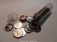 Coins laid out with some loose and others still inside the transparent plastic roll tube labeled 1967.