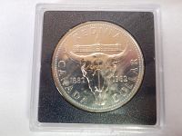 Photo of front side of 1982 Regina Canada Dollar Coin displayed inside clear plastic collector case with black background.