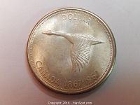 Front side of the 1967 Canadian one dollar coin showing flying goose and centennial dates.