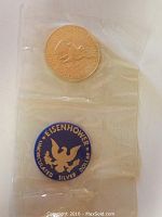 Photo showing sealed one dollar coin and Eisenhower silver dollar token in clear plastic