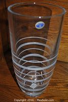Clear crystal vase with horizontal frosted etched rings pattern, tall and cylindrical shape, photographed frontally on wooden surface.