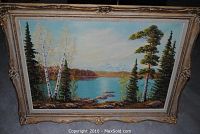 Full view of the framed oil painting showing the lake, trees, and mountainous background.