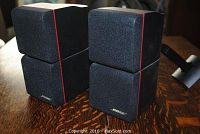 Two black Bose double cube speakers with fabric front and red line detail, stacked in pairs.