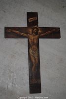 Full view of a wooden crucifix with hand painted image of the crucified Christ, showing the full cross and figure.