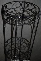 Close-up showing upper tier with circular metal rods and ornamental scrollwork support.