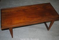 Top-down view of rectangular teak coffee table on concrete floor