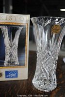 Crystal vase with flared top and intricate cut design, shown next to original box with label and branding.