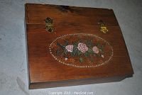 Top view of the closed wooden box showing the hand painted floral design on the slant top lid.