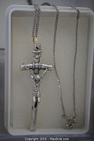 Silver-tone crucifix pendant with detailed Jesus figure and INRI plaque, hanging from chain inside a foam-lined box.