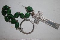 Photo showing green oval glass beads with shamrock embossment linked by silver tone chain, attached to a silver crucifix with Christ figure and a split key ring.