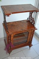 Full front perspective of the two-tier mahogany music cabinet on porcelain casters