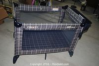 Full view of the Graco portable playard in plaid fabric with mesh sides, showing frame and structure