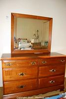 Full front view of the maple dresser with the mirror sitting on top.