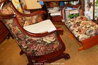 Antique wooden rocking chair with floral upholstery and ottoman next to it.