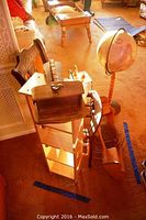 Photo showing antique wooden chair missing seat, tall wooden shelf, globe on stand, and metal hanging baskets on carpeted floor.
