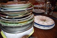 Stacked decorative plates showing various colors and designs, some with hooks for hanging