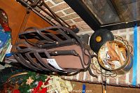 Metallic cylindrical firewood holder filled with firewood pieces, next to the fireplace tools and brick wall.