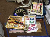 Overview of games including dartboard, toy violin, checkers, Connect Four, puzzles and educational game pieces on carpet floor.