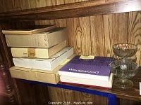 Several boxed plate items including Wedgwood and Carnation, stacked next to three clear glass bowls.
