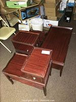 Photo showing the coffee table and two matching side tables stacked on carpeted floor with boxes and chair around.