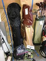 Photo of the two golf bags showing multiple clubs inside and beside bags, including a leather headcover on one club.
