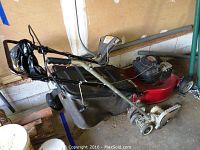 Photo of red and black Quantum Power Signature 2000 Elite lawn mower with attached grass catcher bag and handle controls.