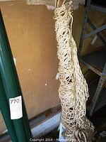 Photo of green metal hammock base pole with item sticker attached to it, measuring about 49x78 inches.