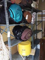 Photo of two large industrial metal storage shelves with multiple items including rolled sleeping bags, a yellow cooler, and a white net.