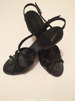 Pair of black snakeskin strappy high heels with ankle straps, front view.