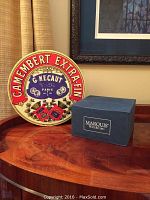 Photo showing Camembert Extra Fin style porcelain platter box and blue Marquis by Waterford tealight box on a wooden table surface.
