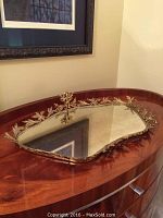 Full view of the vintage styled mirrored vanity tray with gold-tone decorative rim, placed on wooden surface.